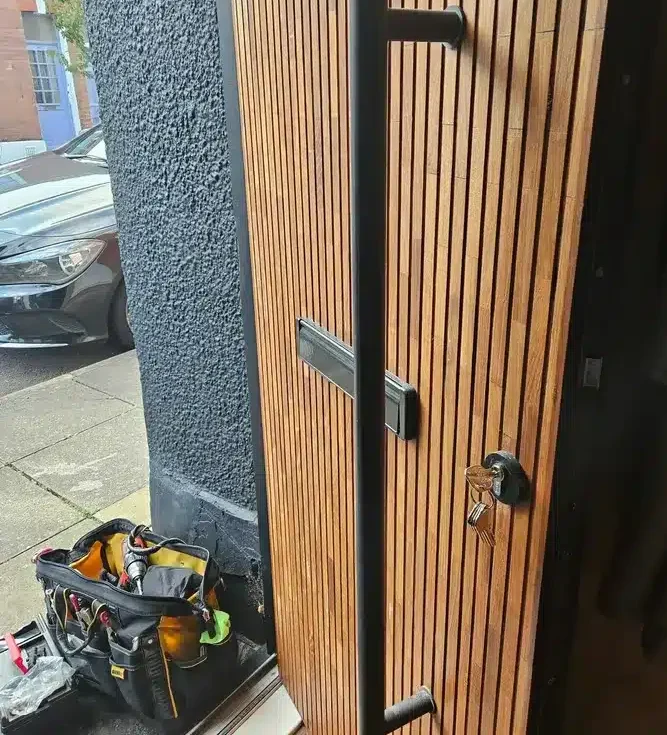 Brown wooden decorated front door with long handle and lock