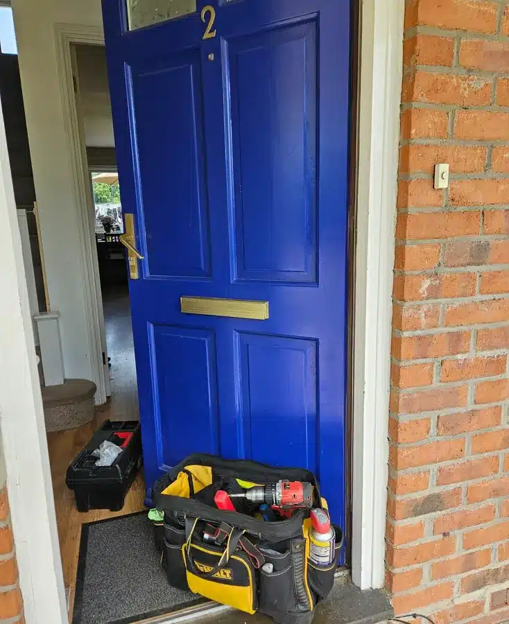 Front door in blue and brass color with locksmith bag on front